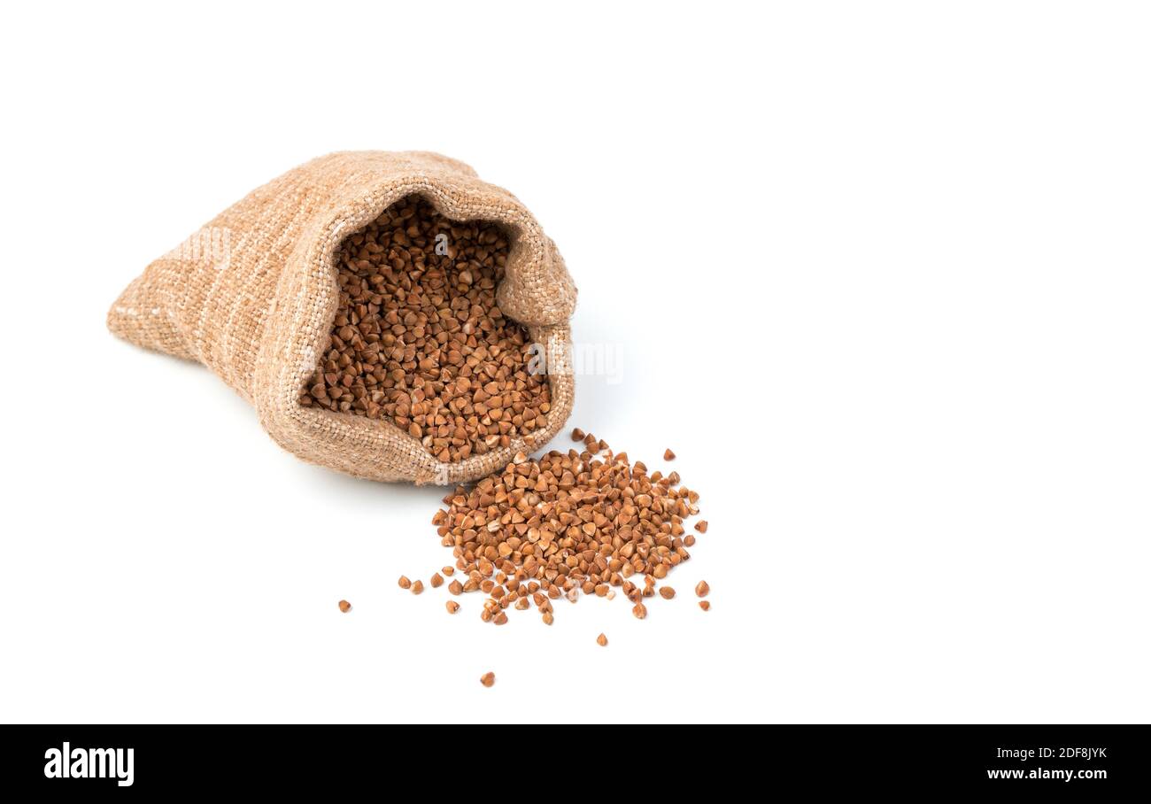 Il grano saraceno viene versato da un sacchetto di lino sul tavolo. Foto Stock