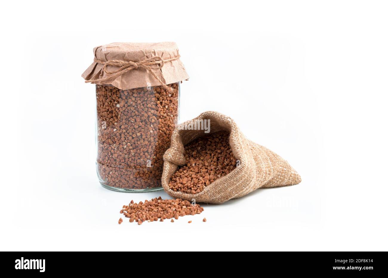 Grano saraceno in un vaso e in un sacchetto di lino su sfondo bianco. Foto Stock
