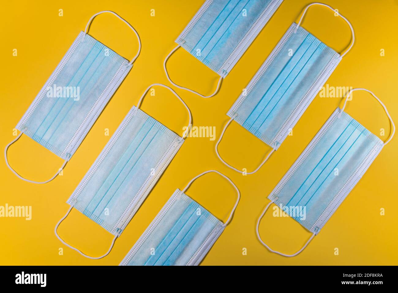 Maschere chirurgiche su sfondo giallo. Maschera medica per la protezione Covid-19 per prevenire la pandemia del coronavirus Foto Stock