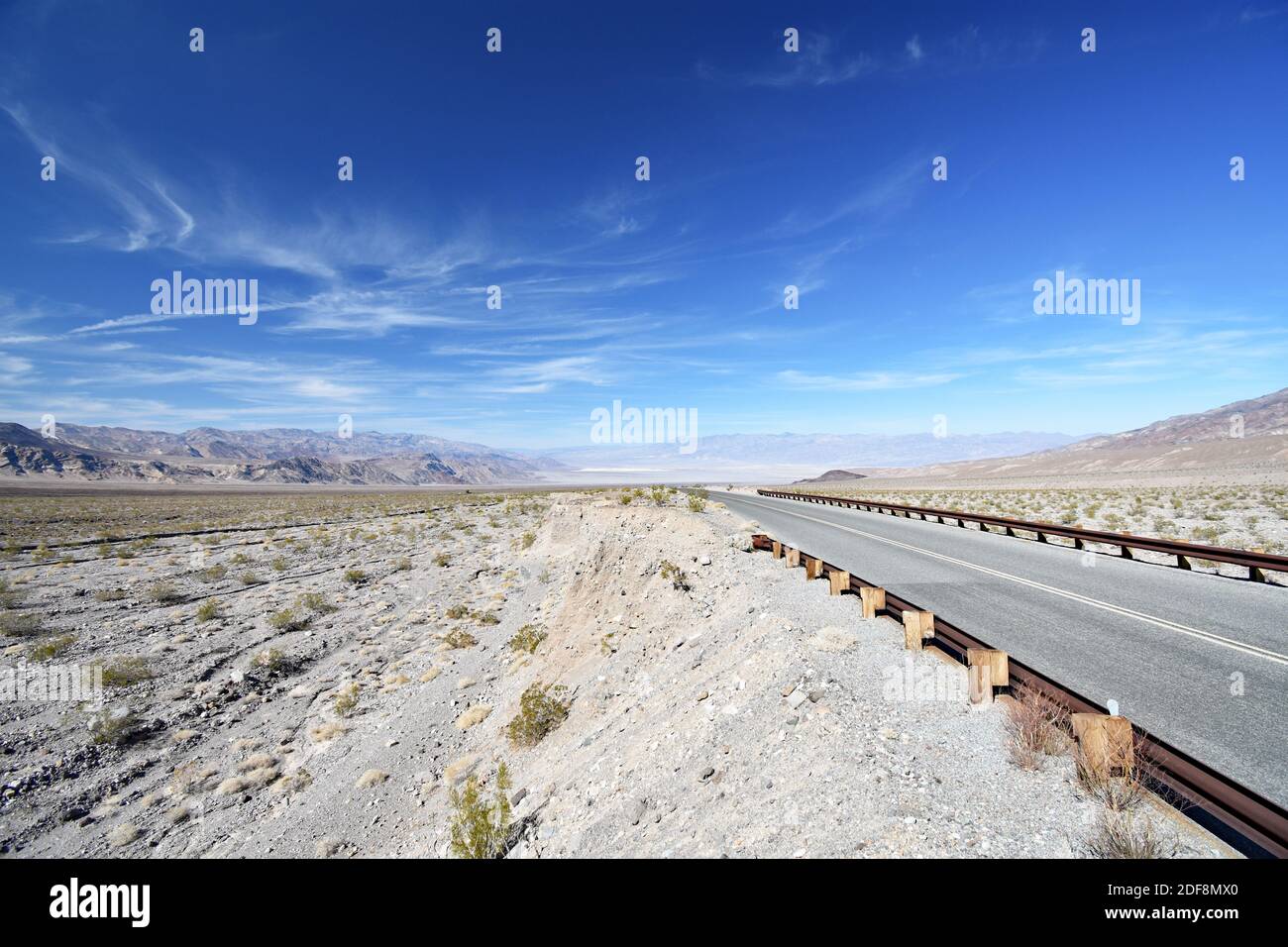 Emigrant Canyon Road, poco prima che si unisca all'autostrada principale che conduce a Stovepipe Wells nel Parco Nazionale della Death Valley. Ringhiera in metallo arrugginito e deserto. Foto Stock