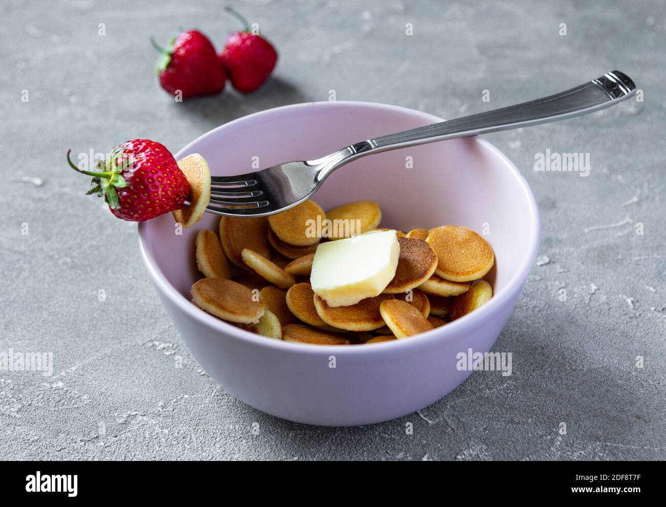Ciotola rosa con minuscola frittella di cereali con fragole. Cucina alla moda Foto Stock