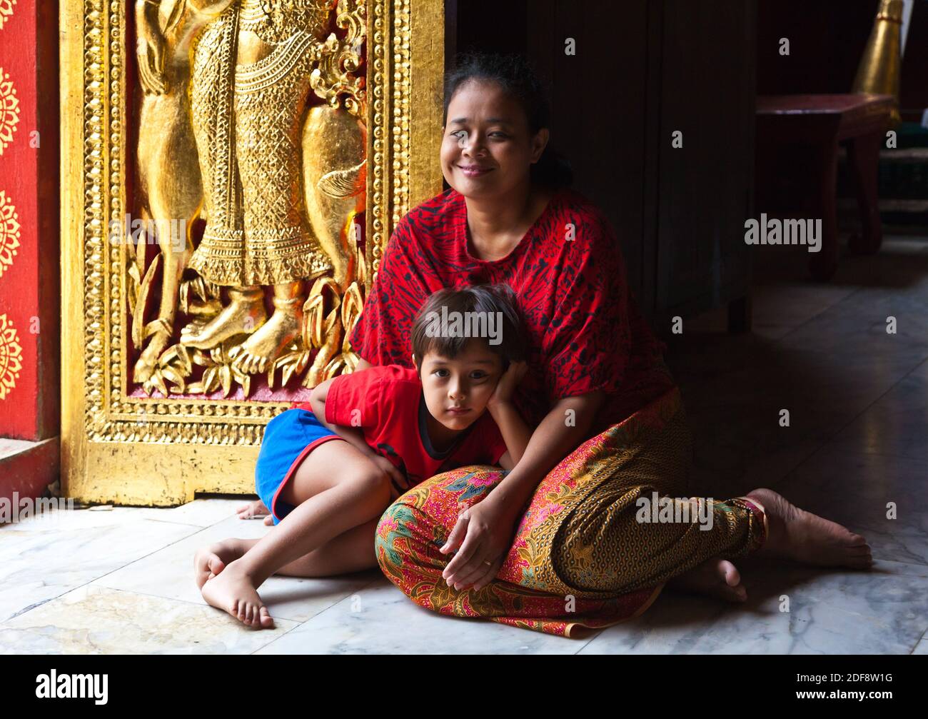 THAI madre e bambino dentro il buddista di Wat Xieng Thong (il Tempio della città d'Oro), costruito nel 1560 - Luang Probang, LAOS Foto Stock