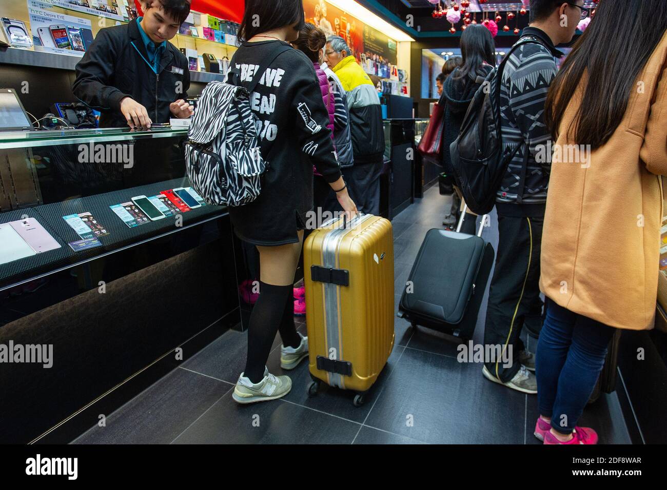 01-22-2015 Hong Kong . giovane donna cinese in un negozio di smartphone a Hong Kong. Ragazza con 1 borsa gialla su ruote Foto Stock