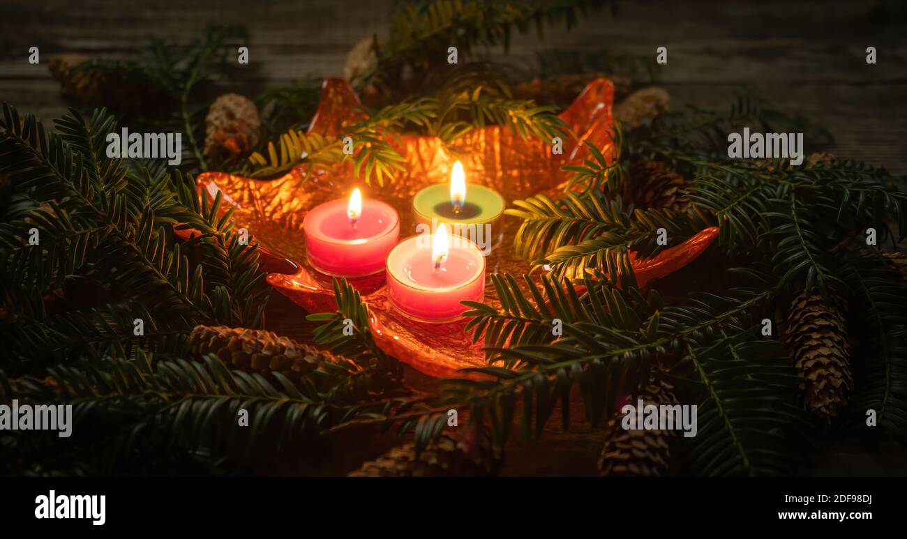 Decorazione di Natale con candele brucianti su sfondo scuro con ramo con aghi. Primo piano e profondità di campo poco profonda. Vacanze di Natale e nuovo Foto Stock