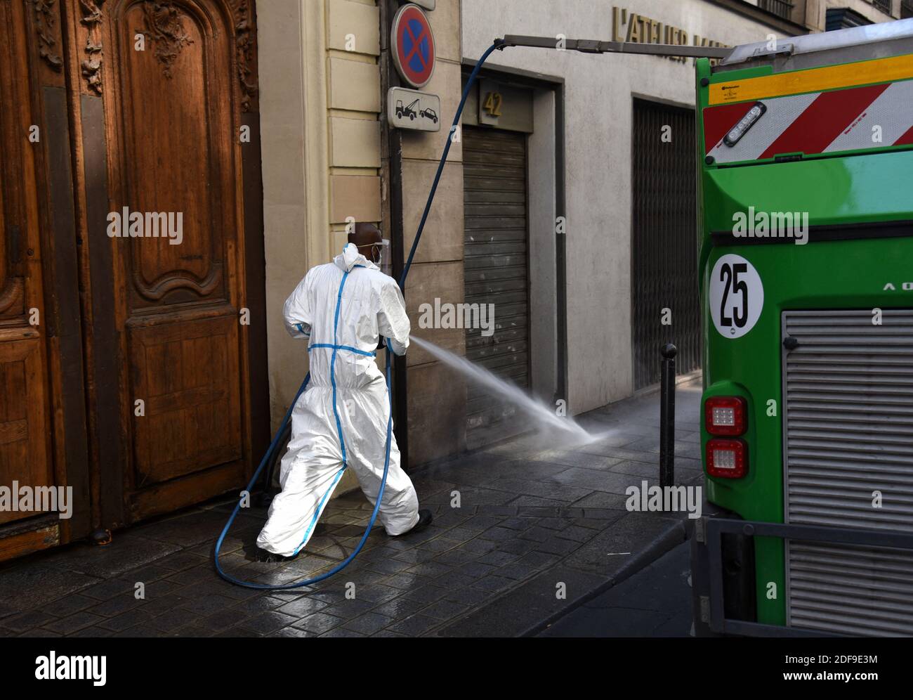 Un servizio urbano pulitore di strada, indossando maschera e guanti, pulire il marciapiede di una strada con una lancia d'acqua a Parigi, Francia, il 24 aprile 2020, come il paese è sotto blocco per fermare la diffusione della pandemia Covid-19 causata dal novo coronavirus. La Mairie di Parigi ha assicurato ai residenti che "non c'è rischio di acqua di rubinetto", dopo che una settimana fa sono state trovate tracce di coronavirus SARS-COV-2 - che causa Covid-19 - nella fonte idrica non potabile della capitale. Le tracce sono state trovate in quattro campioni del 27 prelevati dall'acqua dall'autorità comunale Eau de Paris, guidata dalla Mairie. Questo w Foto Stock
