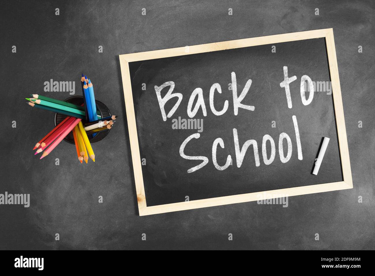 Back to School scritto su lavagna con matita colorata multipla all'interno di un portamatite. Foto Stock