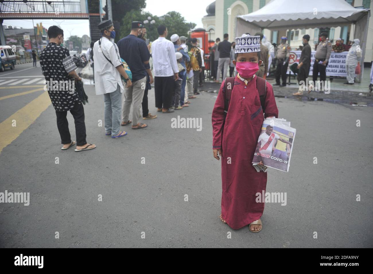 Un bambino, Muhammad Irfan Syahputra, 11, visto durante la vendita del suo giornale per i musulmani che entrano in camera disinfettante presso la moschea di al Mashun celebrata Eid al-Fitr 1441H tra malattia di Coronavirus-19 (COVID-19) focolaio. Photo taken in al Mashun mosque (Grand) mosque of Medan, North Sumatra Province, Indonesia on May 24, 2020. Il governo indonesiano ha portato avanti la task force per l'accelerazione della gestione COVID-19 ha registrato il numero di ulteriori casi positivi COVID-19 confermati al giorno il 23 maggio 2020 alle 12.00, aumentando a 949 persone, portando il totale a 21,745. Un chil Foto Stock