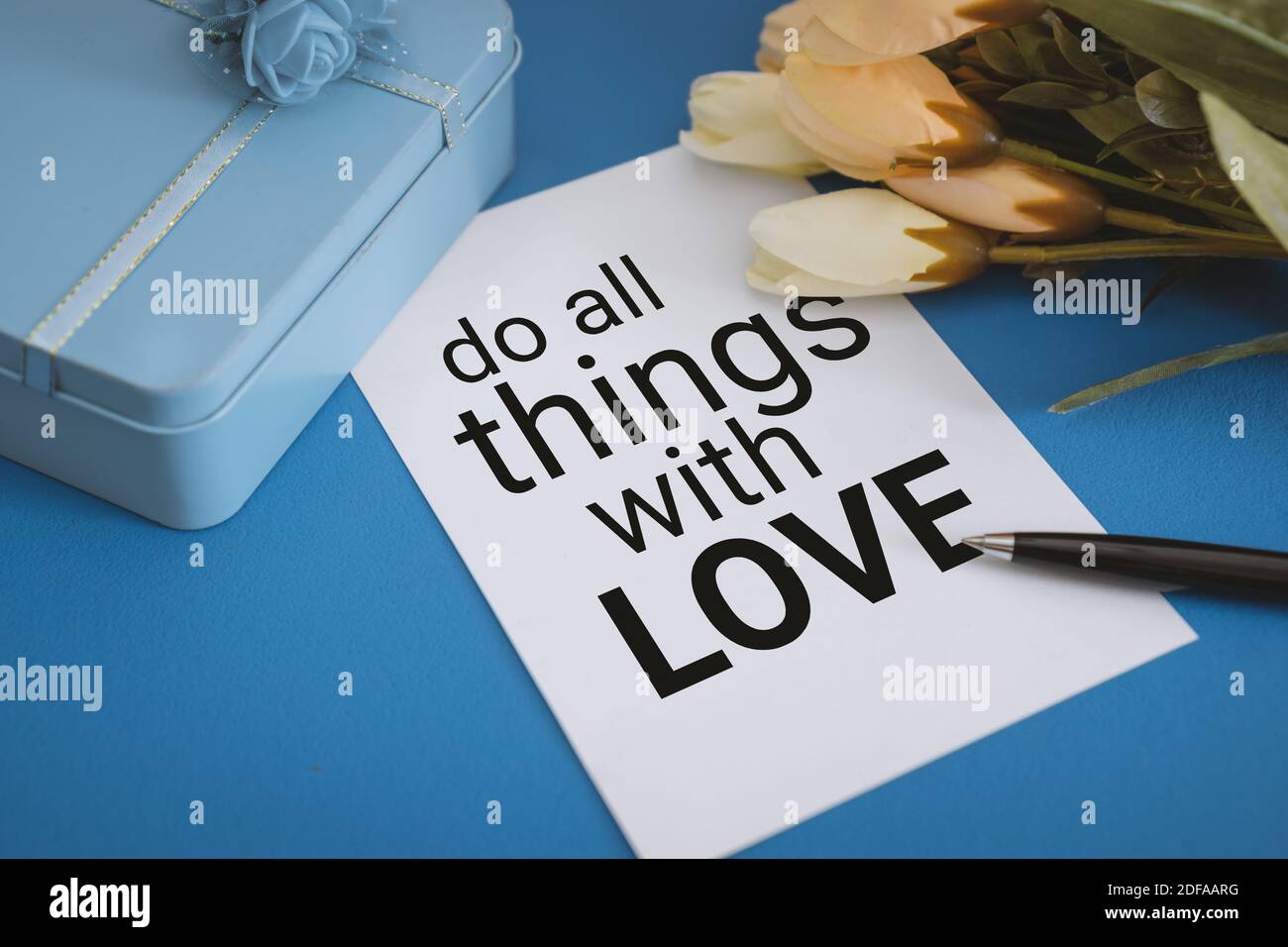 Primo piano della vista carta con preventivo, confezione regalo e fiore su sfondo blu pastello Foto Stock
