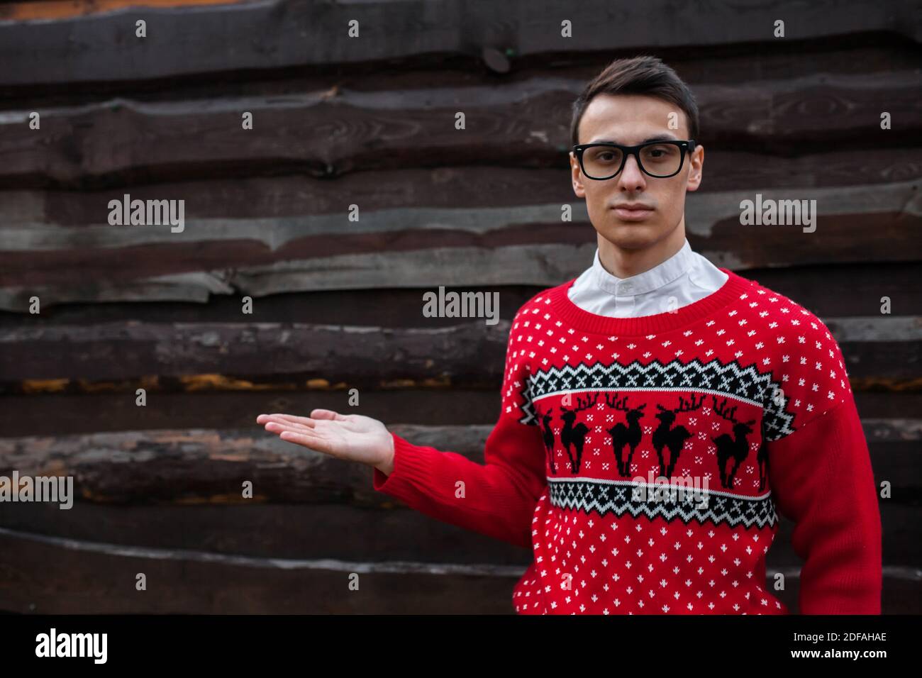 Il ritratto del ragazzo nel maglione di Natale sullo sfondo di un muro di legno. Luogo isolato per la foto Foto Stock