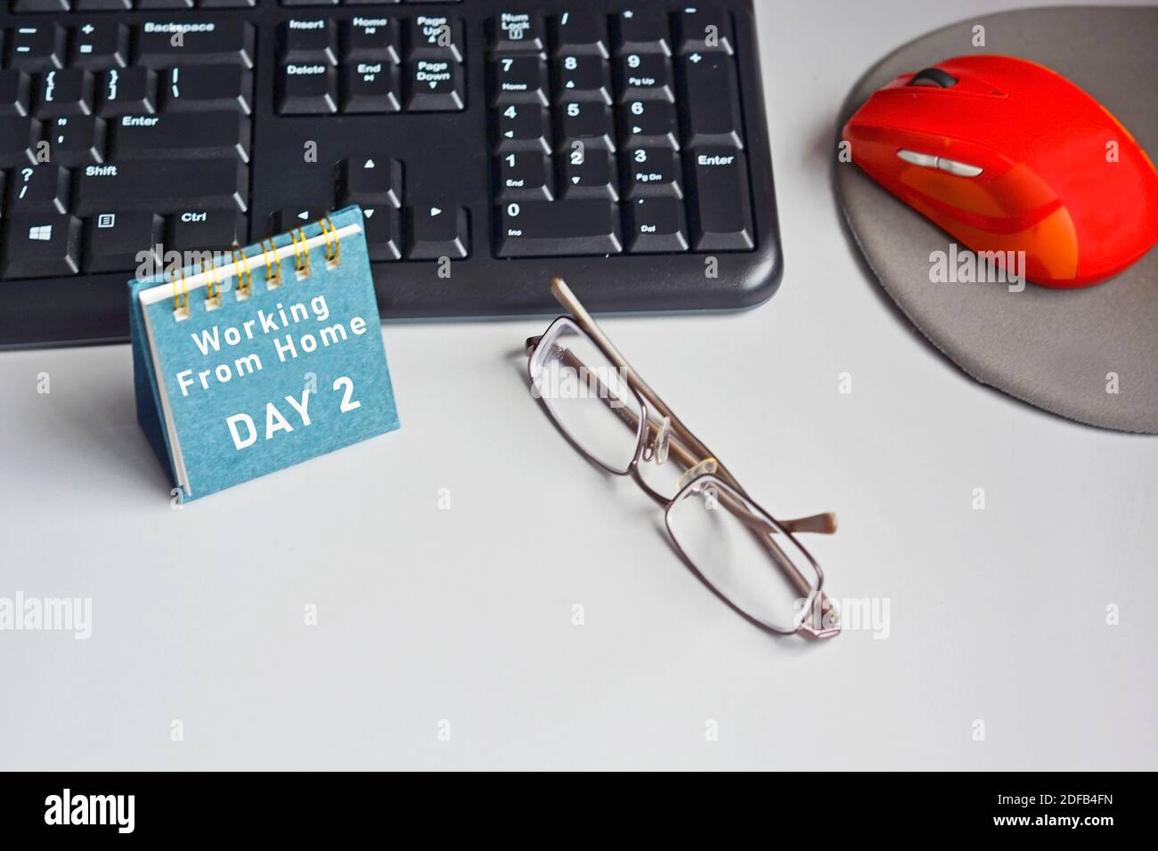 Scrivania con tastiera, mouse, occhiali e calendario con testo Foto Stock