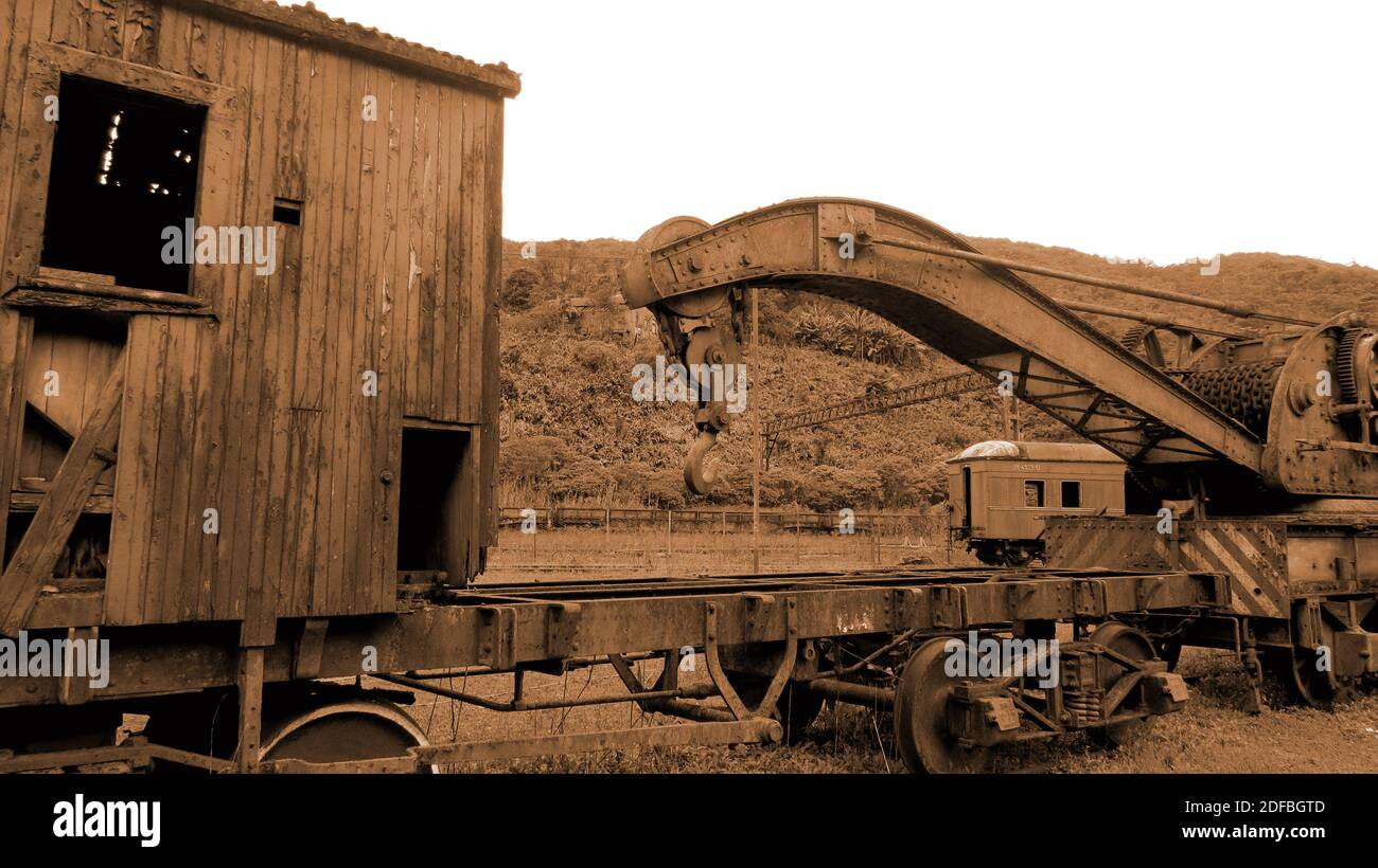 Vagone arrugginito e abbandonato fuori dalla ferrovia. Il carro marcio si trova in una foresta tropicale [colori seppia] Foto Stock