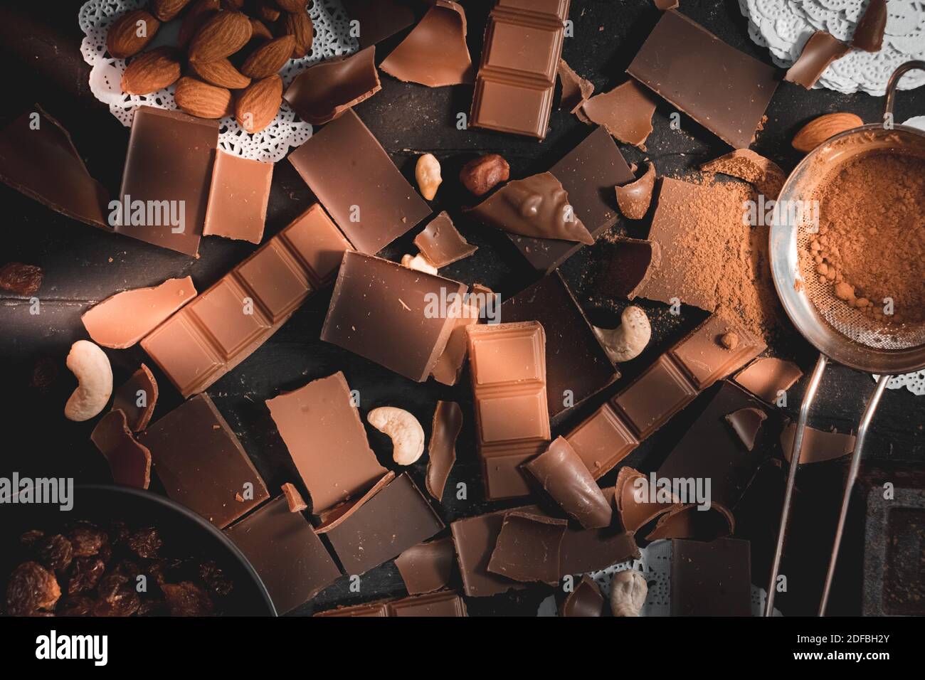 Cioccolato vista dall'alto ingredienti per cucinare con cioccolato, noci, cacao in polvere e uvetta rustica facendo sfondo al dessert Foto Stock