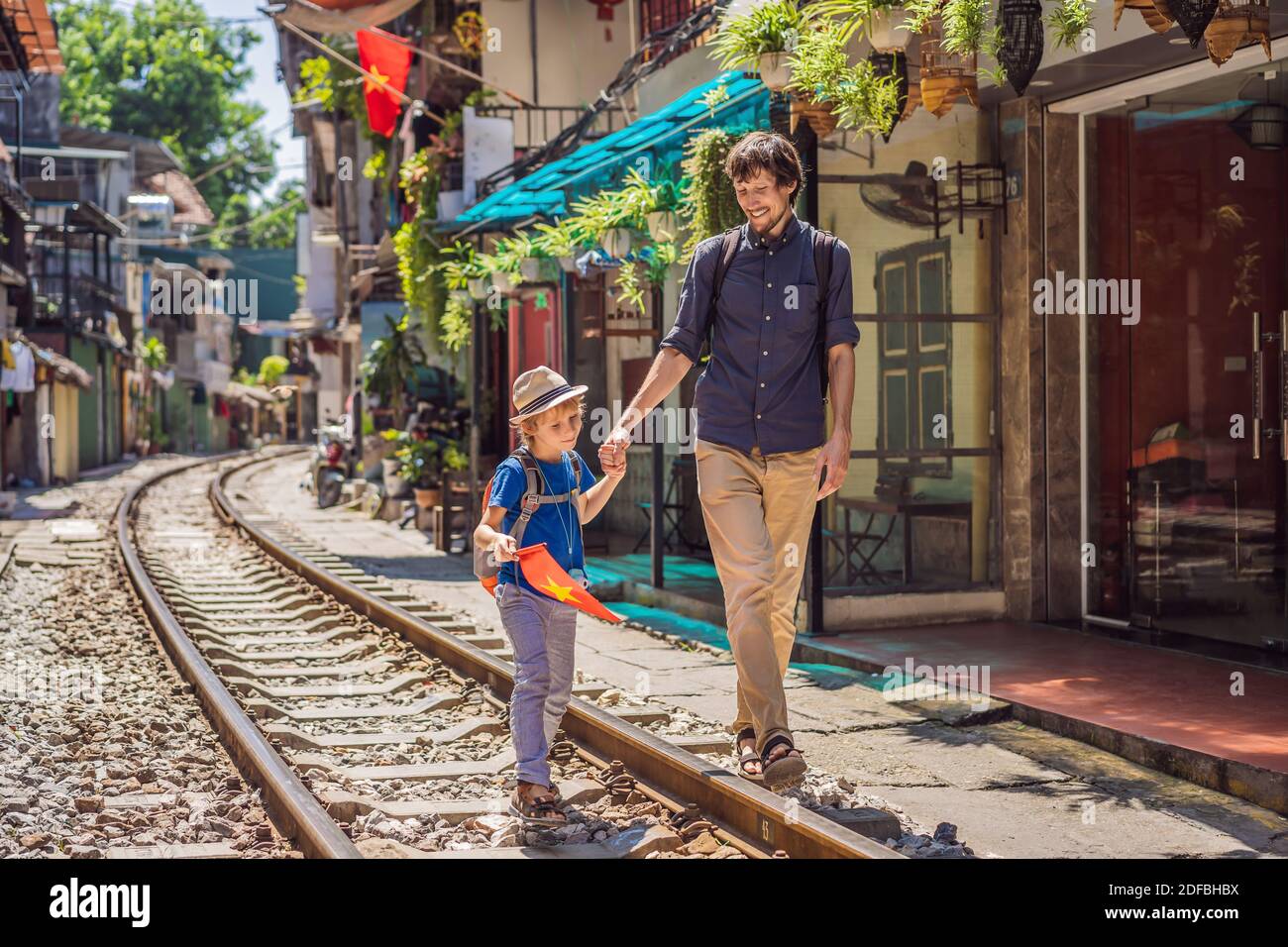 I viaggiatori del padre e del figlio camminano intorno ai percorsi ferroviari che passano attraverso l'area residenziale nella città di Hanoi. Hanoi Train Street è una famosa destinazione turistica Foto Stock