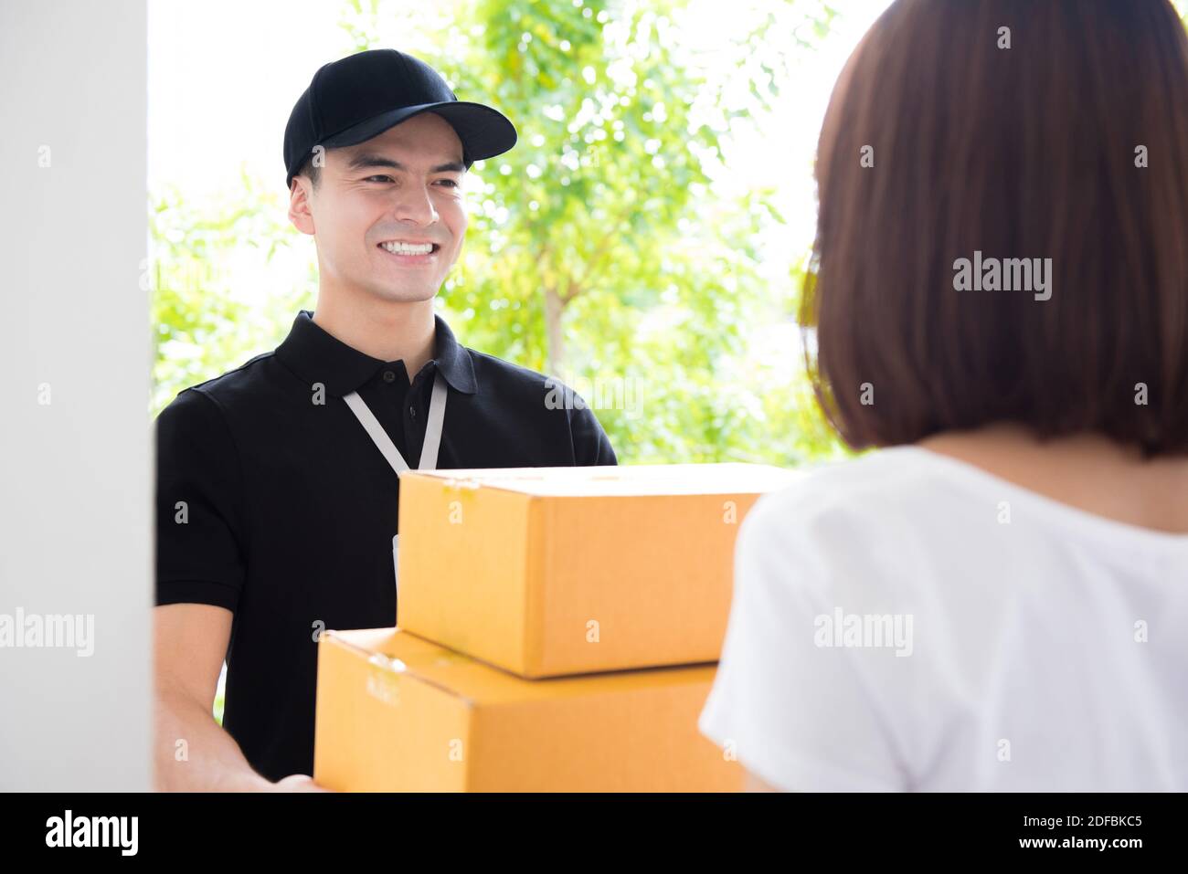 Sorridente uomo di consegna consegnare i pacchetti a una donna - corriere concetto Foto Stock