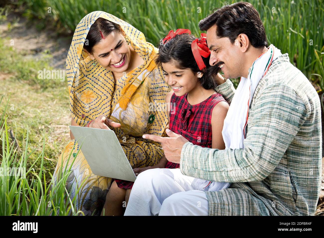 Famiglia rurale che utilizza un computer portatile sul campo agricolo Foto Stock