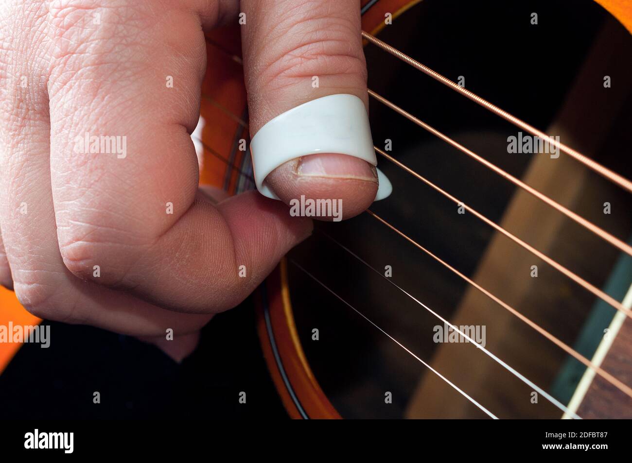 Dettaglio di una mano del chitarrista usando un thumbpick to riproduci la musica con le dita e selezionale con le dita Foto Stock