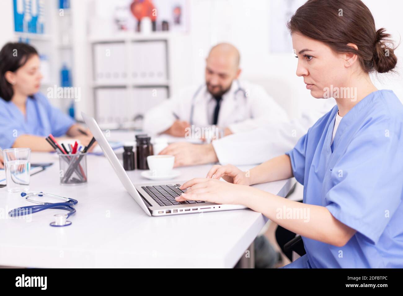 Primo piano del medico che prende appunti sul portatile durante il seminario medico con esperti di medicina. Terapeuta clinica che parla con i colleghi di malattia, medico Foto Stock