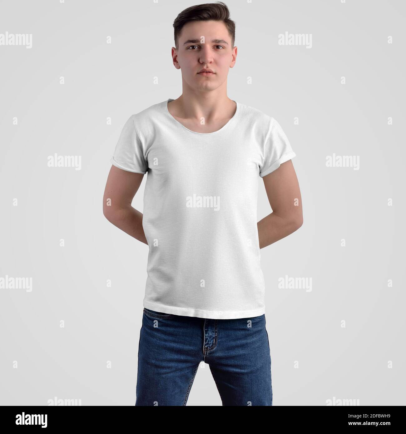 Modello T-shirt su un ragazzo in jeans blu, vista frontale. Mockup di abiti di moda su sfondo bianco per la presentazione del design. Foto Stock