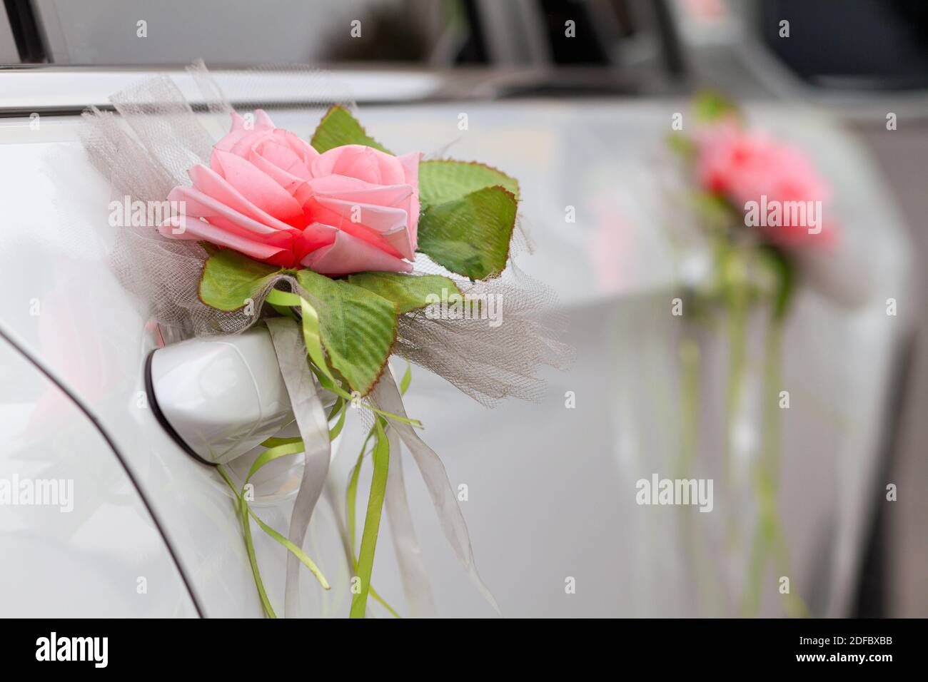 Bella auto bianca decorata con fiore rosa boutonniere per il sposa e sposo il giorno del matrimonio Foto Stock