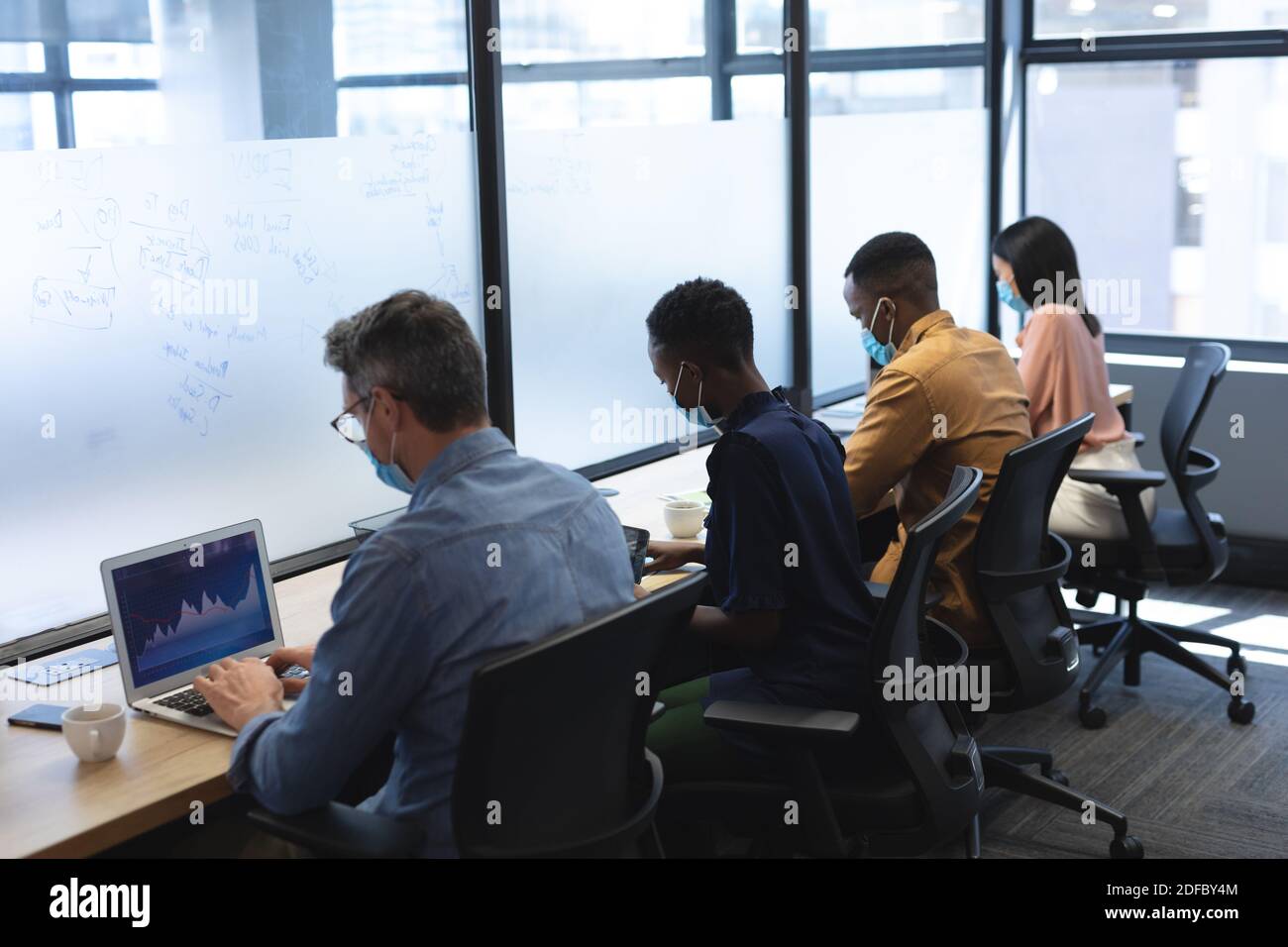 Diversi colleghi indossano maschere per il viso che lavorano in ufficio Foto Stock