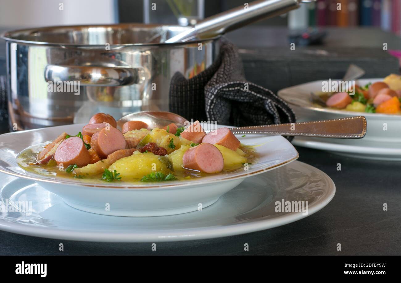 Un piatto di zuppa di patate servito su un tavolo da cucina a casa con pentola Foto Stock