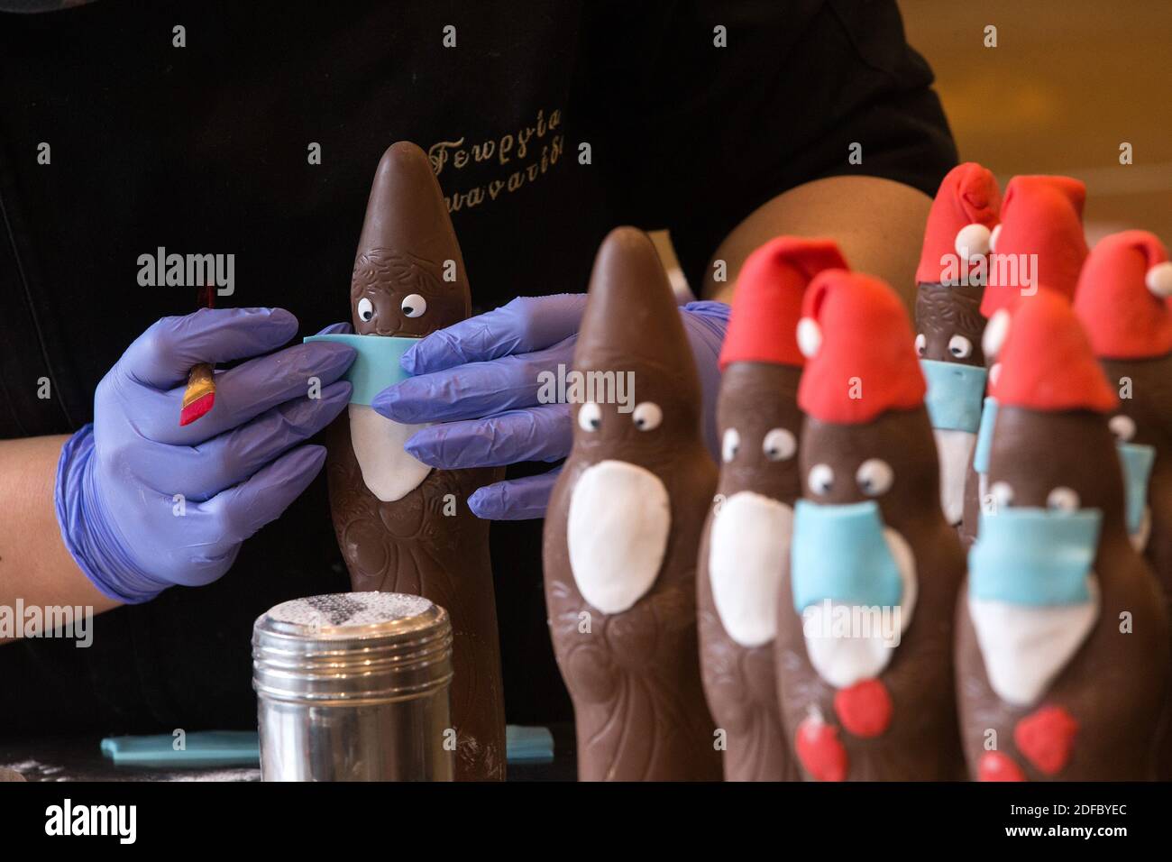 (201204) -- ATHENS, 4 dicembre 2020 (Xinhua) -- un membro del personale della pasticceria di Tassos Vazakas decora le clausole di cioccolato mascherato Santa, ad Atene, Grecia, il 3 dicembre 2020. Le pasticcerie rimangono aperte durante il secondo blocco del paese, che è stato prorogato fino al 14 dicembre. (Foto di Marios Lolos/Xinhua) Foto Stock