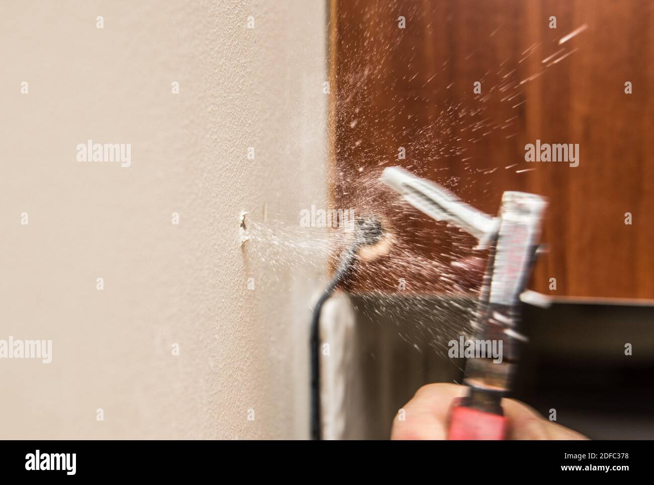 Vista ravvicinata della persona che rimuove manualmente il vecchio tassello in plastica, il tappo da parete in nylon dalla parete asciutta con le pinze a casa. Concetto di ristrutturazione dell'abitazione. Foto Stock