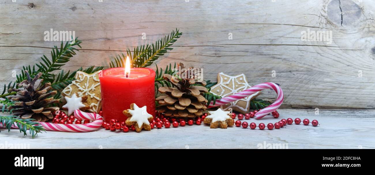 Candela rossa e decorazione di Natale su tavole di legno grigio freddo, formato banner panoramico, spazio copia, fuoco selezionato, profondità di campo stretta Foto Stock