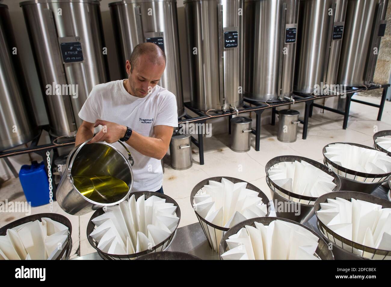 Francia, Alpes Maritime, Grasse, distilleria Fragonard, impianto di filtrazione dell'olio essenziale, 1 dipendente versa il liquido nei filtri Foto Stock