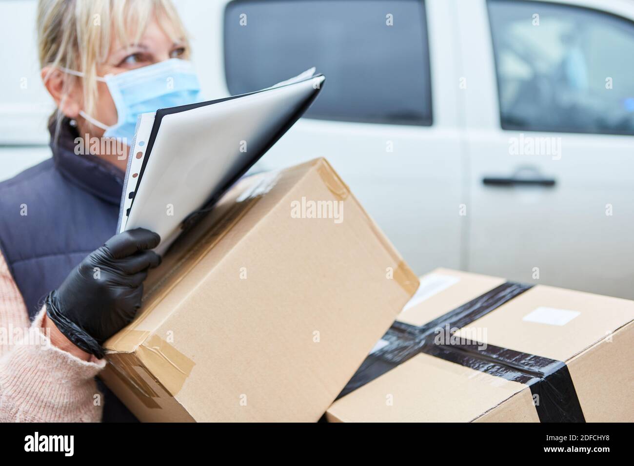 Gestore pacchi per un servizio di consegna con maschera facciale durante la consegna dei pacchi Foto Stock