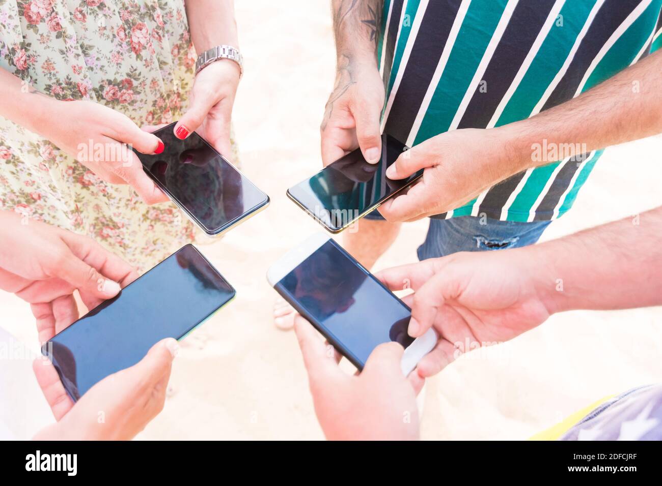 vista dall'alto delle mani che chiacchierano con i loro telefoni cellulari di un gruppo di giovani amici. concetto di amicizia, tecnologia e comunicazione globale Foto Stock