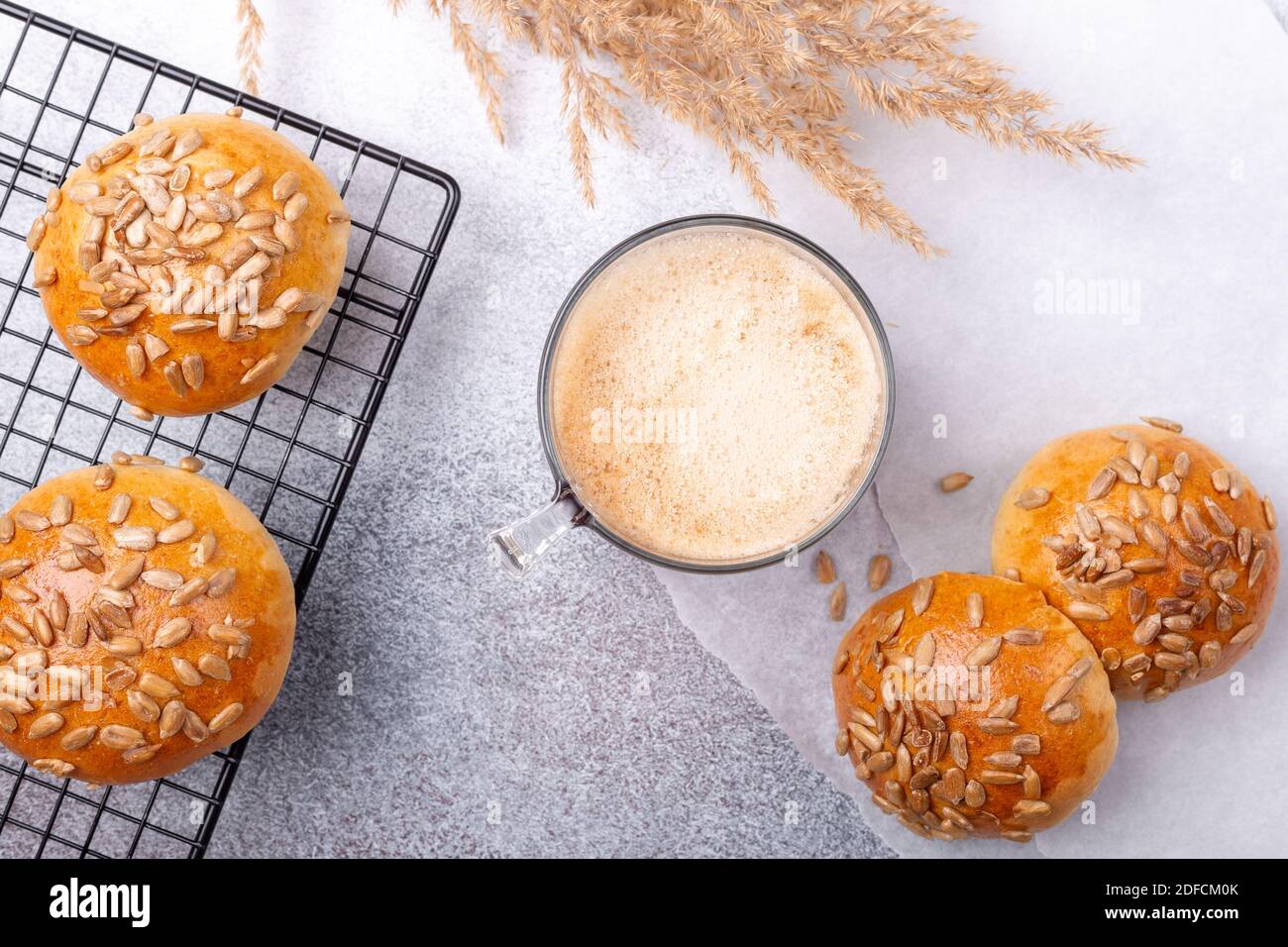 Caffè e panini freschi fatti in casa con semi sulla griglia di raffreddamento. Colazione con caffè e dolci. Vista dall'alto - immagine Foto Stock