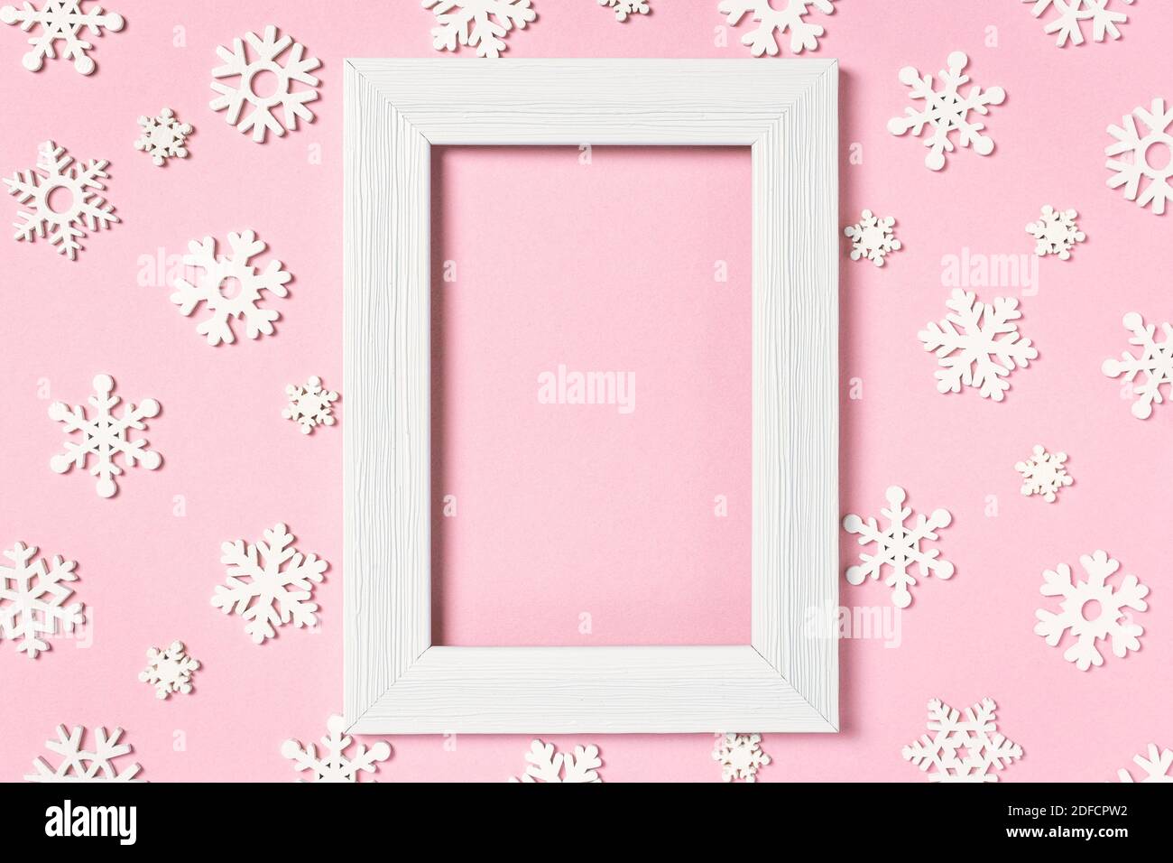 Composizione invernale. Cornice fotografica e fiocchi di neve su sfondo rosa pastello. Concetto di vacanza invernale. Vista dall'alto, disposizione piatta, spazio per la copia. Foto Stock