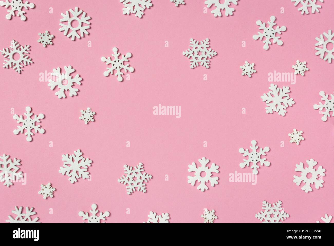 Composizione natalizia fatta di fiocchi di neve su sfondo rosa pastello. Concetto invernale. Disposizione piatta, vista dall'alto, spazio per la copia. Foto Stock