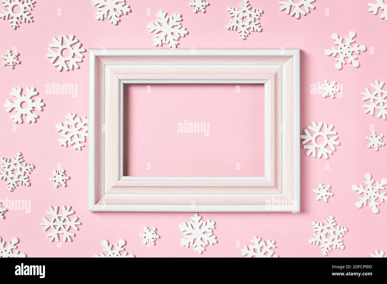 Composizione invernale. Cornice fotografica e fiocchi di neve su sfondo rosa pastello. Concetto di vacanza invernale. Vista dall'alto, disposizione piatta, spazio per la copia. Foto Stock
