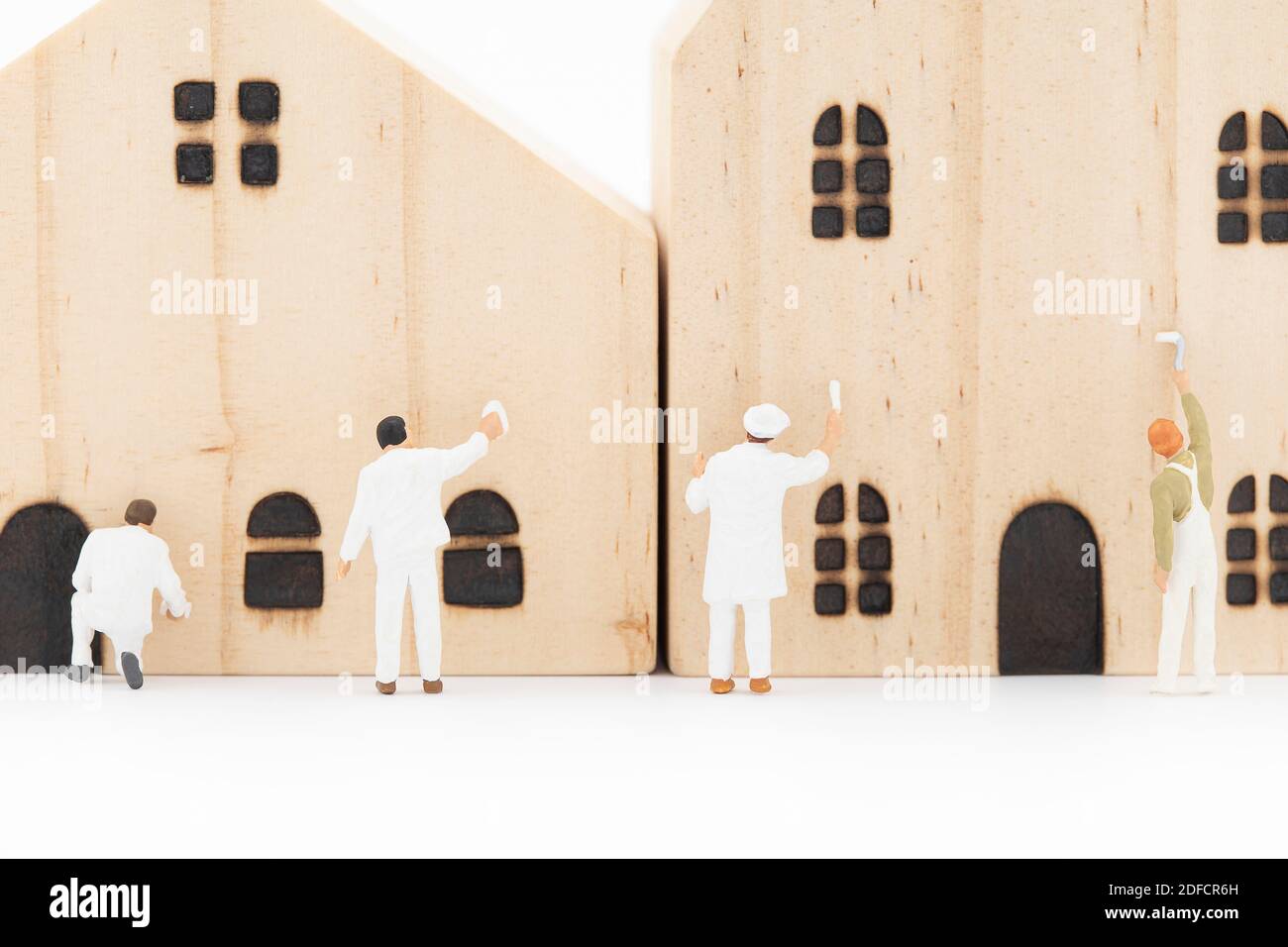 Il pittore in miniatura sta dipingendo la casa in legno modello. Foto Stock
