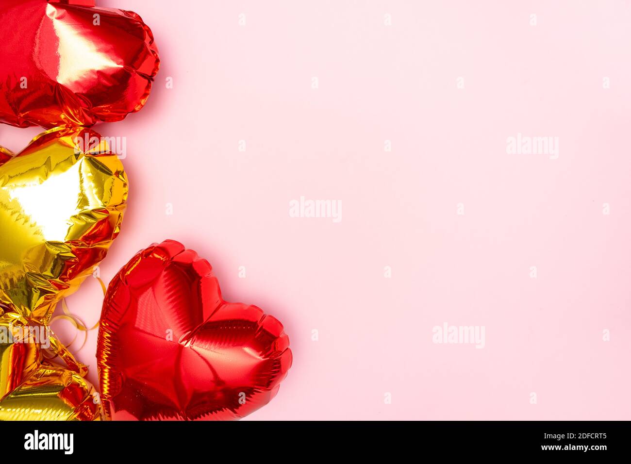 I cuori rossi e dorati lamano palloncini vista superiore sullo sfondo rosa del giorno di San Valentino. CopySpace Foto Stock