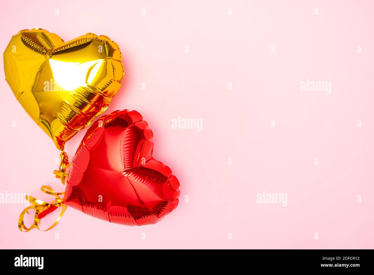 I cuori rossi e dorati lamano palloncini vista superiore sullo sfondo rosa del giorno di San Valentino. CopySpace Foto Stock