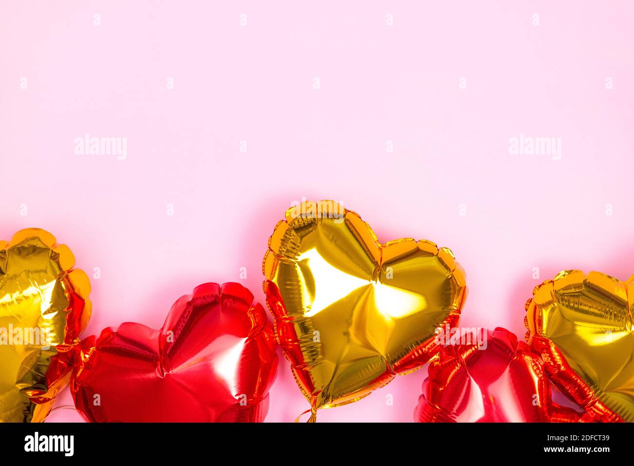 Cornice per testo con cuori rossi e dorati palloncini in foglio vista superiore su sfondo rosa San Valentino. CopySpace Foto Stock
