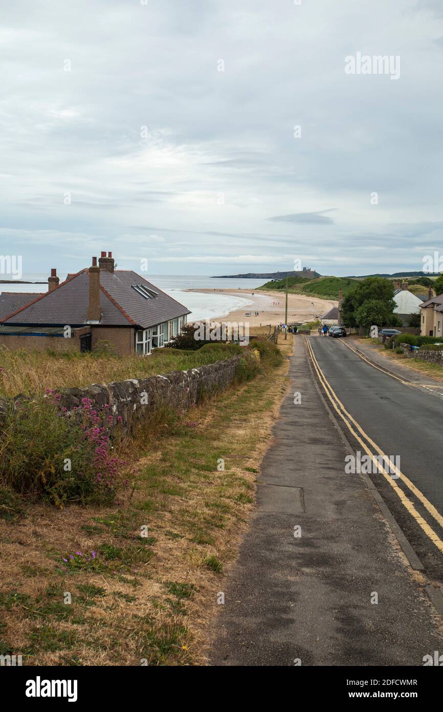 La strada che conduce a bassa Newton sul mare con il castello di Dunstanburgh in background in Northumberland,l'Inghilterra,UK Foto Stock