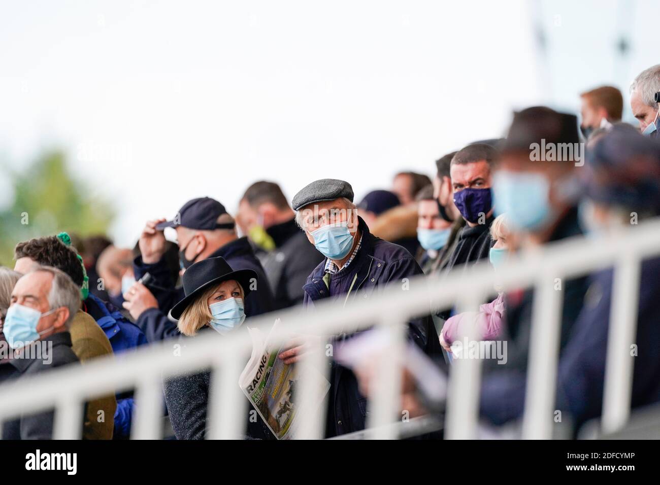 I racegoisti indossano rivestimenti per il viso all'ippodromo di Sandown Park. Foto Stock