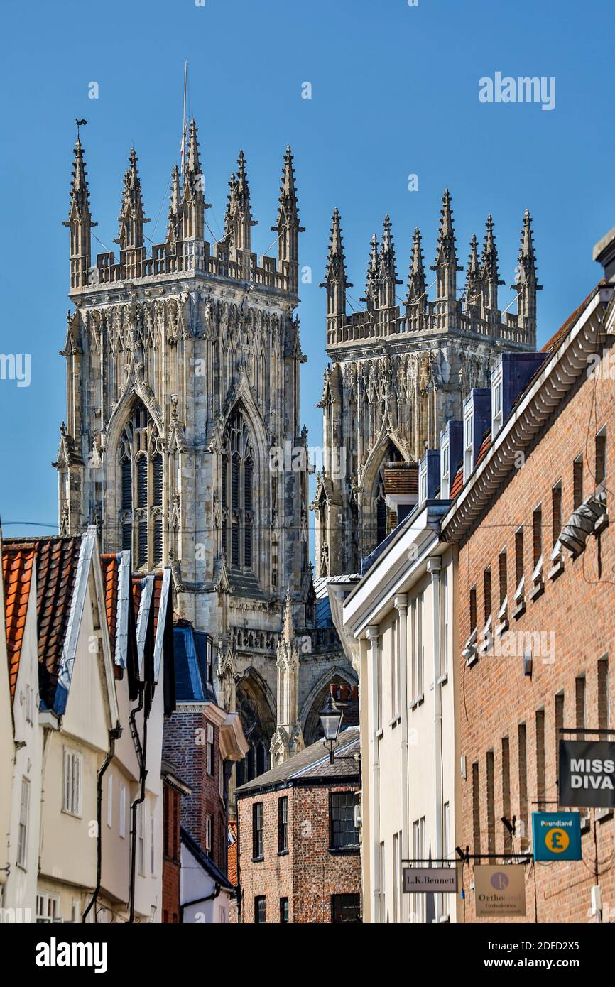 Negozi, insegne e torri di York Minster (la Cattedrale e la Chiesa Metropolitan di San Pietro) nel retro, York, Yorkshire, Inghilterra, Regno Unito Foto Stock
