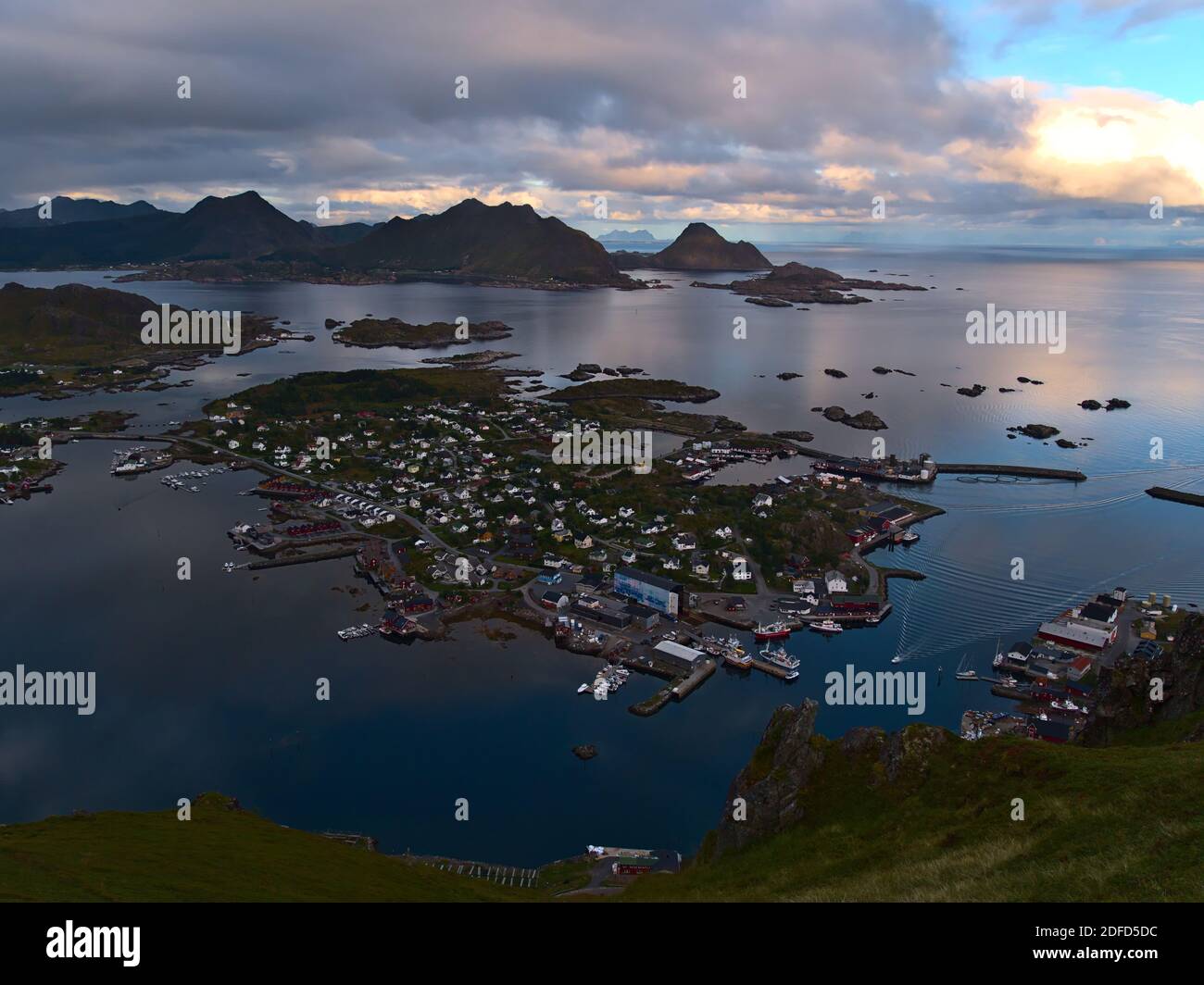 Splendida vista panoramica aerea del villaggio di pescatori Ballstad sulla costa dell'isola di Vestvågøya, Lofoten, Norvegia con porto, magazzini e aspre montagne. Foto Stock