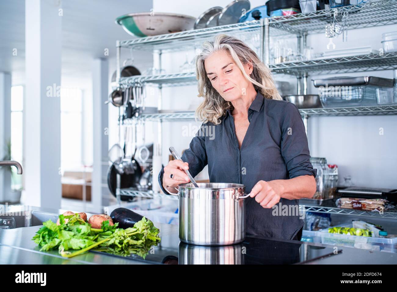 Donna che cucina su un piano cottura a induzione. Foto Stock