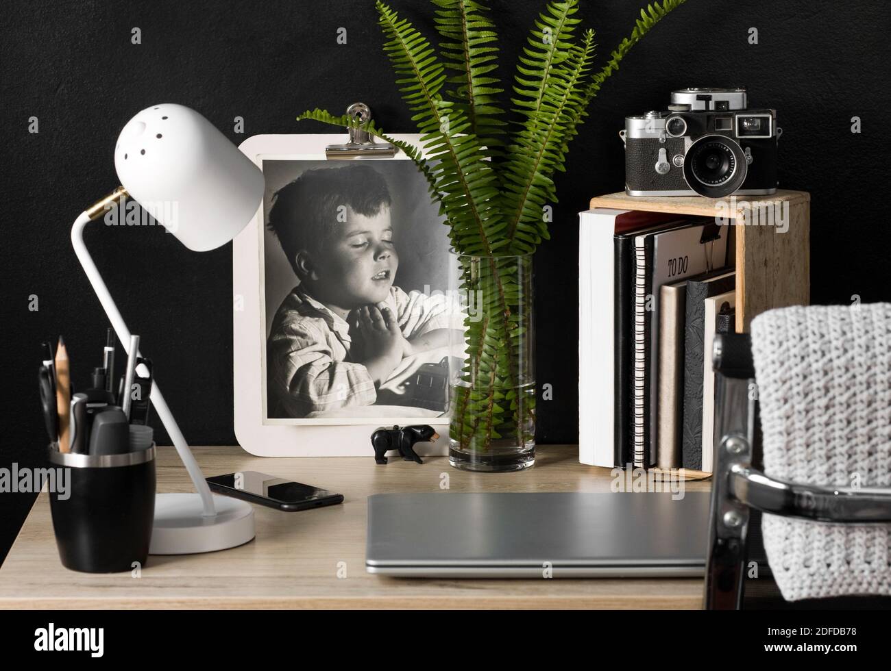 Uno spazio organizzato per l'ufficio domestico con una fotocamera vintage. Il decor color crema, nero e argento creano un'atmosfera rilassata per lavorare in modo produttivo da casa. Foto Stock