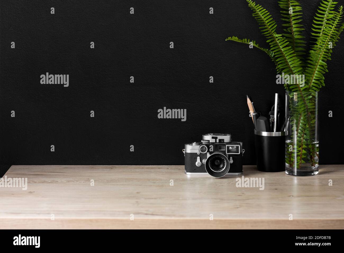 Uno spazio organizzato per l'ufficio domestico con una fotocamera vintage. Il decor color crema, nero e argento creano un'atmosfera rilassata per lavorare in modo produttivo da casa. Foto Stock