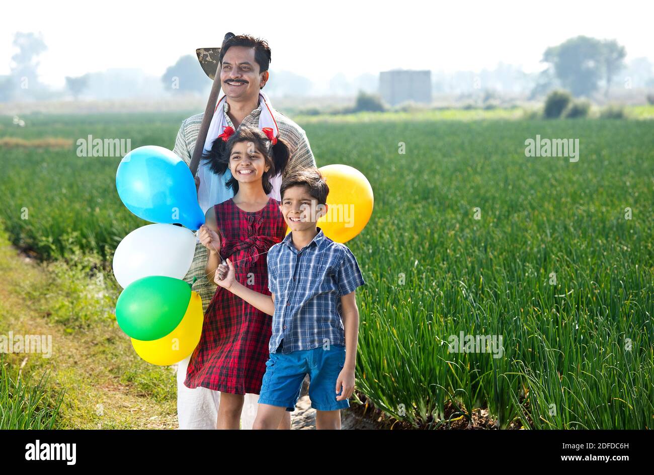 Felice famiglia indiana di contadino con palloncini in campo agricolo Foto Stock