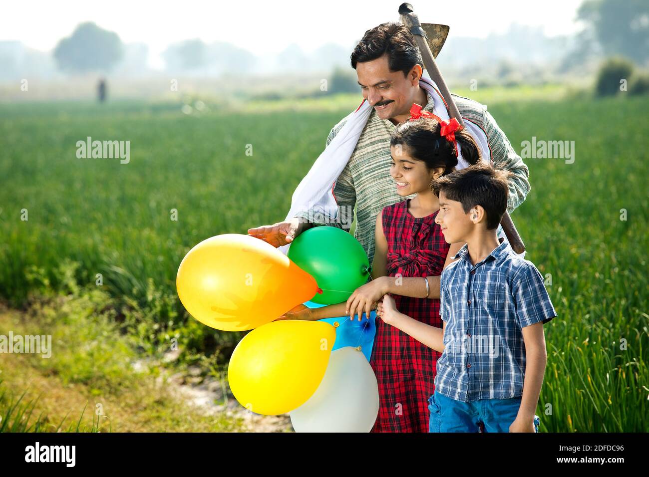 Felice famiglia indiana di contadino con palloncini in campo agricolo Foto Stock