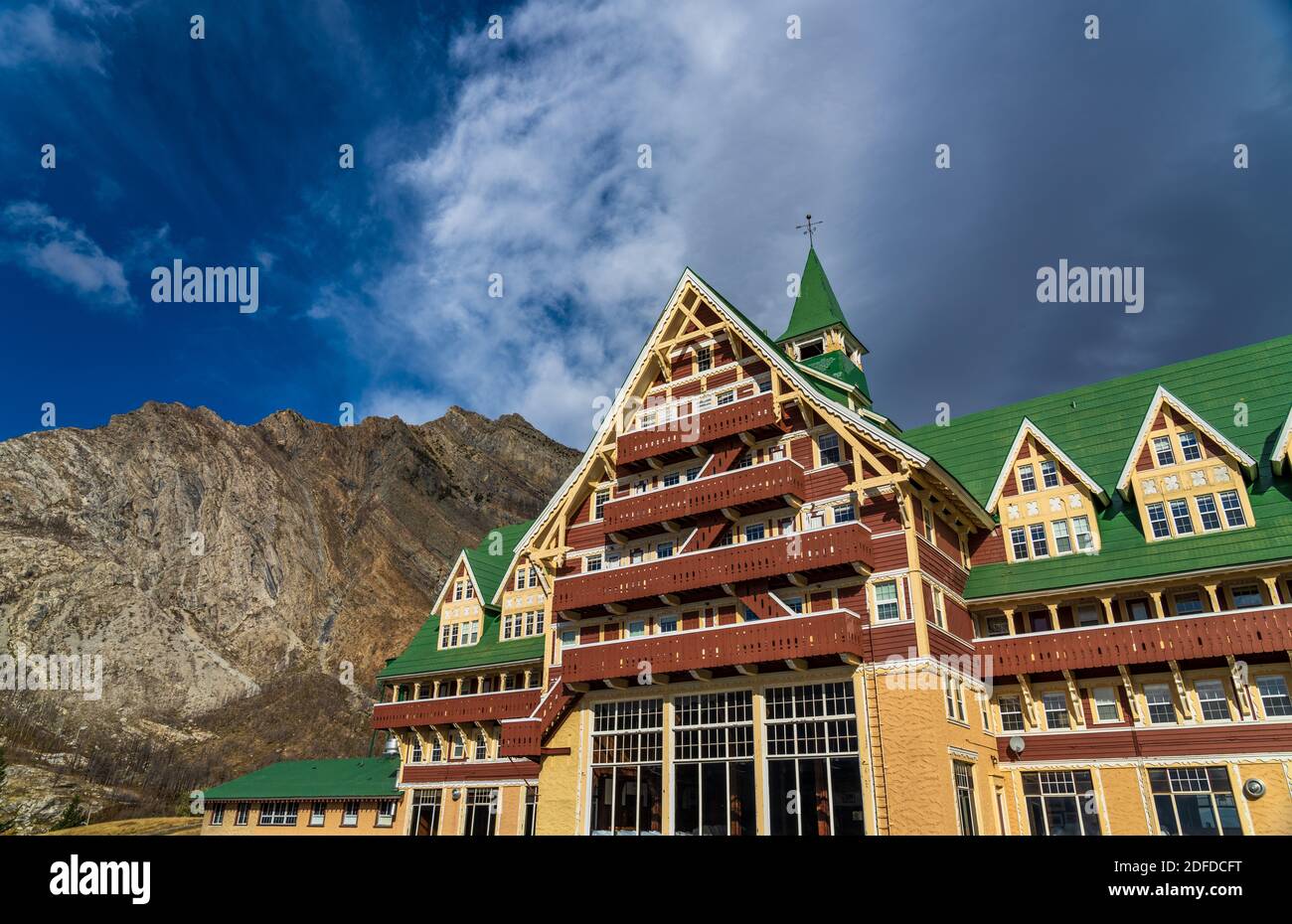 Prince of Wales Hotel in autunno giorno di sole mattina. Cielo blu, nuvole bianche sulle montagne sullo sfondo. Punti di riferimento nel parco nazionale dei laghi di Waterton Foto Stock