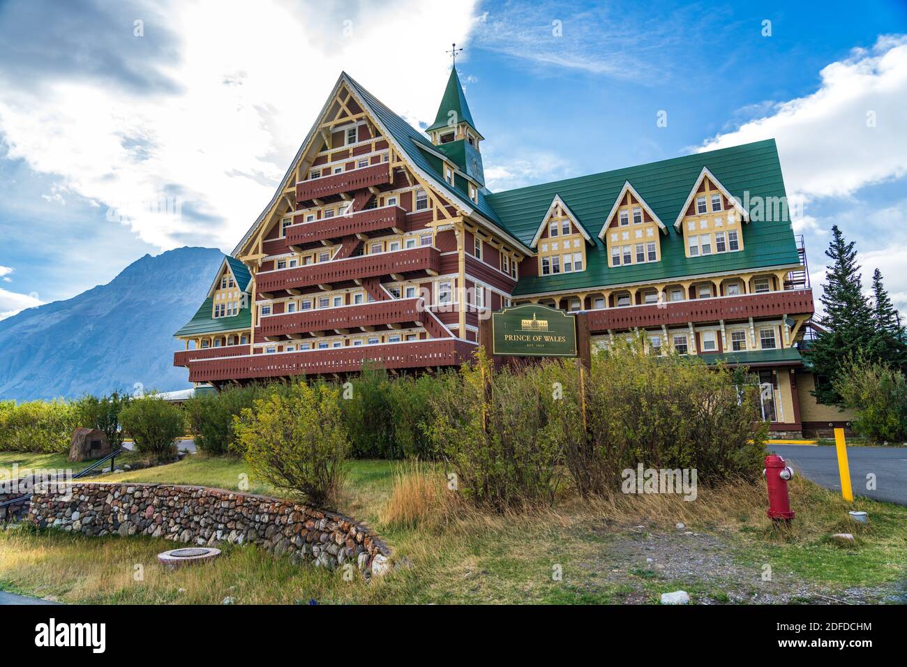 Prince of Wales Hotel in autunno giorno di sole mattina. Cielo blu, nuvole bianche sulle montagne sullo sfondo. Punti di riferimento nel parco nazionale dei laghi di Waterton Foto Stock